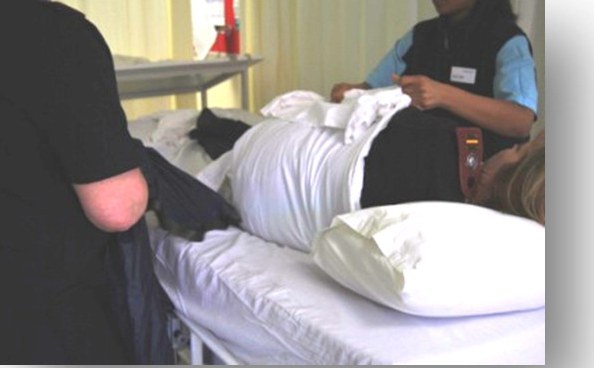Two carers turning a patient in bed using the EASI-SLIDE sliding sheet